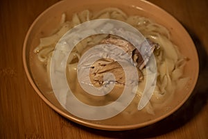 Chicken Noodle Soup. Chicken and noodle soup on an orange tablecloth in an orange plate. Food photography. Hot dish