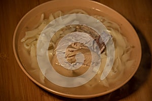 Chicken Noodle Soup. Chicken and noodle soup on an orange tablecloth in an orange plate. Food photography. Hot dish