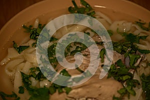 Chicken Noodle Soup. Chicken and noodle soup on an orange tablecloth in an orange plate. Food photography. Hot dish