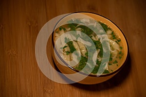 Chicken Noodle Soup. Chicken and noodle soup on an orange tablecloth in an orange plate. Food photography. Hot dish