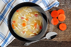 Chicken noodle soup, overhead scene on rustic wood