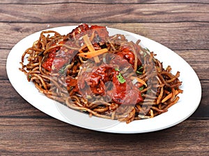Chicken Noodles a popular indo chinese dish made with chicken, noodles and vegetables, served over a rustic wooden background,