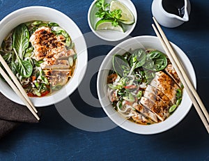 Chicken, noodles and vegetables asian style soup on a blue background