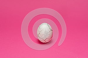 Chicken organic white egg  with cracked like paint. Pink background. Minimal Easter background