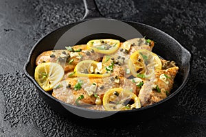 Chicken Piccata with capers, white wine sauce in iron cast pan. Italian food