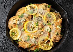 Chicken Piccata with capers, white wine sauce in iron cast pan. Italian food