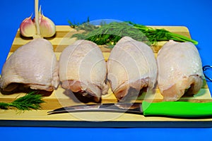 Chicken pieces on a wooden board on a blue background.