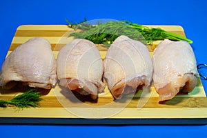 Chicken pieces on a wooden board on a blue background.