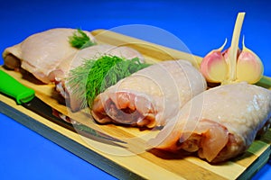 Chicken pieces on a wooden board on a blue background.