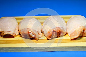 Chicken pieces on a wooden board on a blue background.