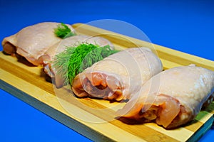 Chicken pieces on a wooden board on a blue background.