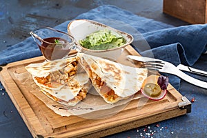 Chicken Quesadillas on Wooden Cutting Board on blue background