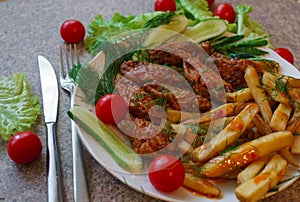 Chicken ribs in honey sauce with french fries and vegetables