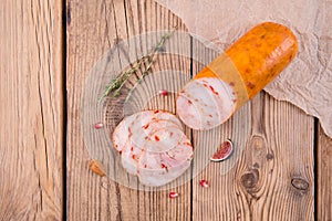 Chicken roll with paprika lies on an old wooden table with a sprig of thyme, almonds, pomegranate and figs. top view. background