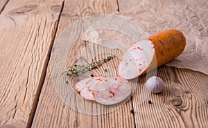 Chicken roll with paprika lies on an old wooden table with a sprig of thyme and garlic