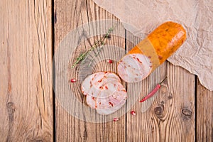 Chicken roll with paprika lies on an old wooden table with a sprig of thyme, pomegranate seeds and hot chili. top view. background