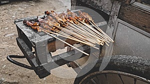 Chicken satay being grilled on a traditional grill on a cart.  Sate is a typical dish of Madura, Indonesia