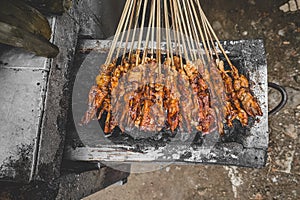 Chicken satay being grilled on a traditional grill on a cart.  Sate is a typical dish of Madura, Indonesia