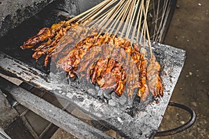 Chicken satay being grilled on a traditional grill on a cart.  Sate is a typical dish of Madura, Indonesia