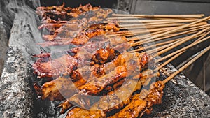 Chicken satay being grilled on a traditional grill on a cart.  Sate is a typical dish of Madura, Indonesia