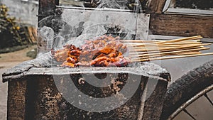 Chicken satay being grilled on a traditional grill on a cart.  Sate is a typical dish of Madura, Indonesia