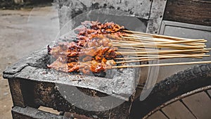 Chicken satay being grilled on a traditional grill on a cart.  Sate is a typical dish of Madura, Indonesia