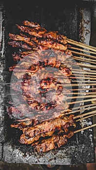 Chicken satay being grilled on a traditional grill on a cart.  Sate is a typical dish of Madura, Indonesia