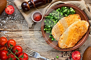 Chicken schnitzel with or cordon bleu with green salad and cherry tomatoes in a rustic style on the old wooden background