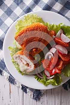 Chicken schnitzel cordon bleu and a salad close-up. vertical top