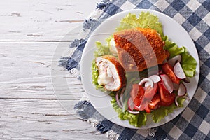 Chicken schnitzel cordon bleu and a salad. Horizontal top view