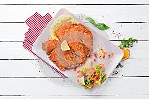 Chicken schnitzel with mashed potatoes on a plate. On a wooden background.