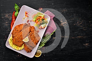 Chicken schnitzel with mashed potatoes on a plate. On a wooden background.