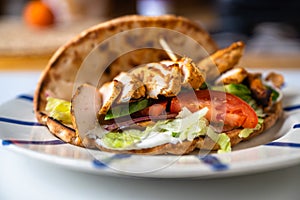 Chicken shawarma in pita bread with vegetable salad on plate on table