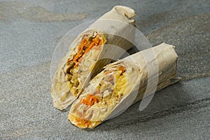 Chicken Shawarma wrapped in lavash on stone background. Greek Gyros roll. Turkish grilled donner