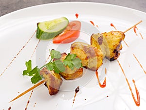 Chicken skewer on a white plate with parsley
