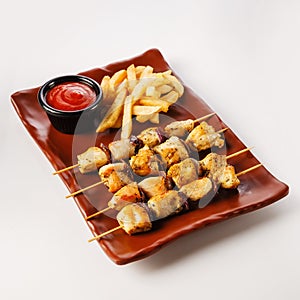 Chicken skewers. Pieces of tender chicken fillet, grilled with sweet onion rings, and garnished with french fries