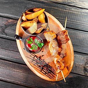 Chicken skewers with sauce and potatoes fries in a bucket