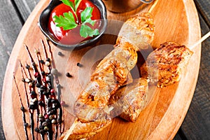 Chicken skewers with sauce and potatoes fries in a bucket on wooden cutting board