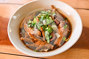 chicken soup with chicken leg feet and wings in red soup bowl and vegetable spring onion - stewed with chinese herbs