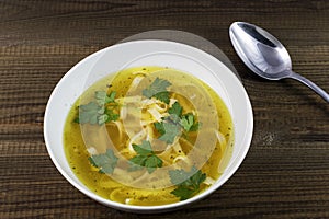 Chicken soup with noodles and parsley leaves.