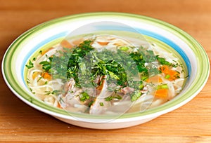 Chicken soup with noodles and vegetables in ceramic bowl