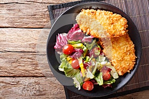 Chicken steak in breading Panko and fresh salad close-up on the