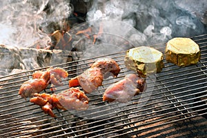 Chicken steaks on a grill grid over a campfire, white smoke, grilled meat and Camembert cheese over a campfire. Summer barbecue