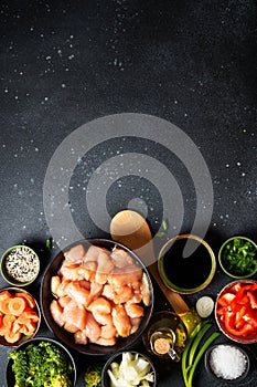 Chicken stir fry with vegetables cooking ingredients at black background.