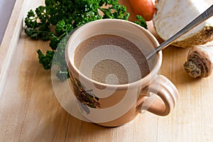 Chicken stock in a vintage mug with a spoon and vegetables