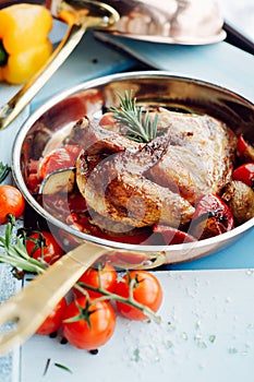 Chicken Tabaka in a pan with vegetables and tomatoes