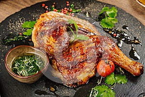 Chicken Tabaka with sauce on stone plate.