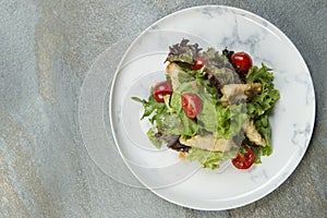 Chicken Tempura Salad on white marble plate, stone anthracite background