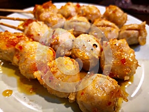 Chicken tendon meatballs plug into wooden stick and then grill.