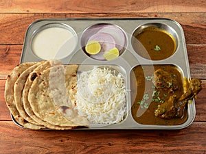 Chicken Thali from an indian cuisine, food platter consists of Chicken curry, lentils, steamed rice, curd and onions., selective